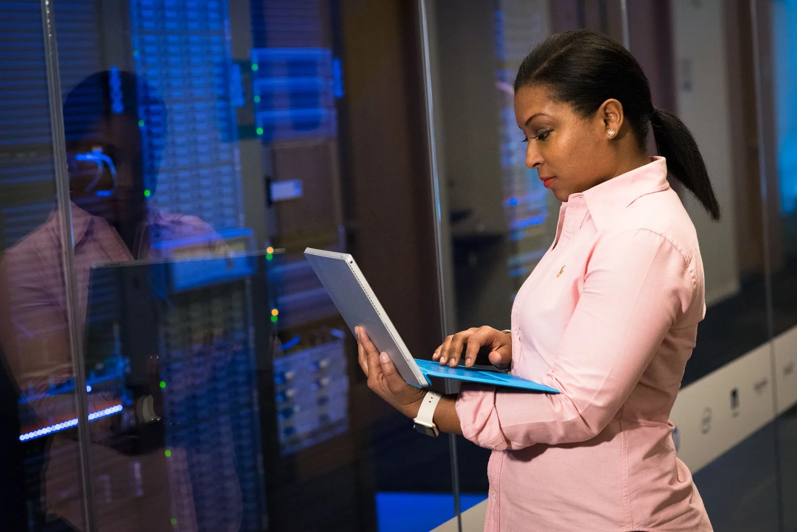 IT engineer using a laptop beside server cabinets