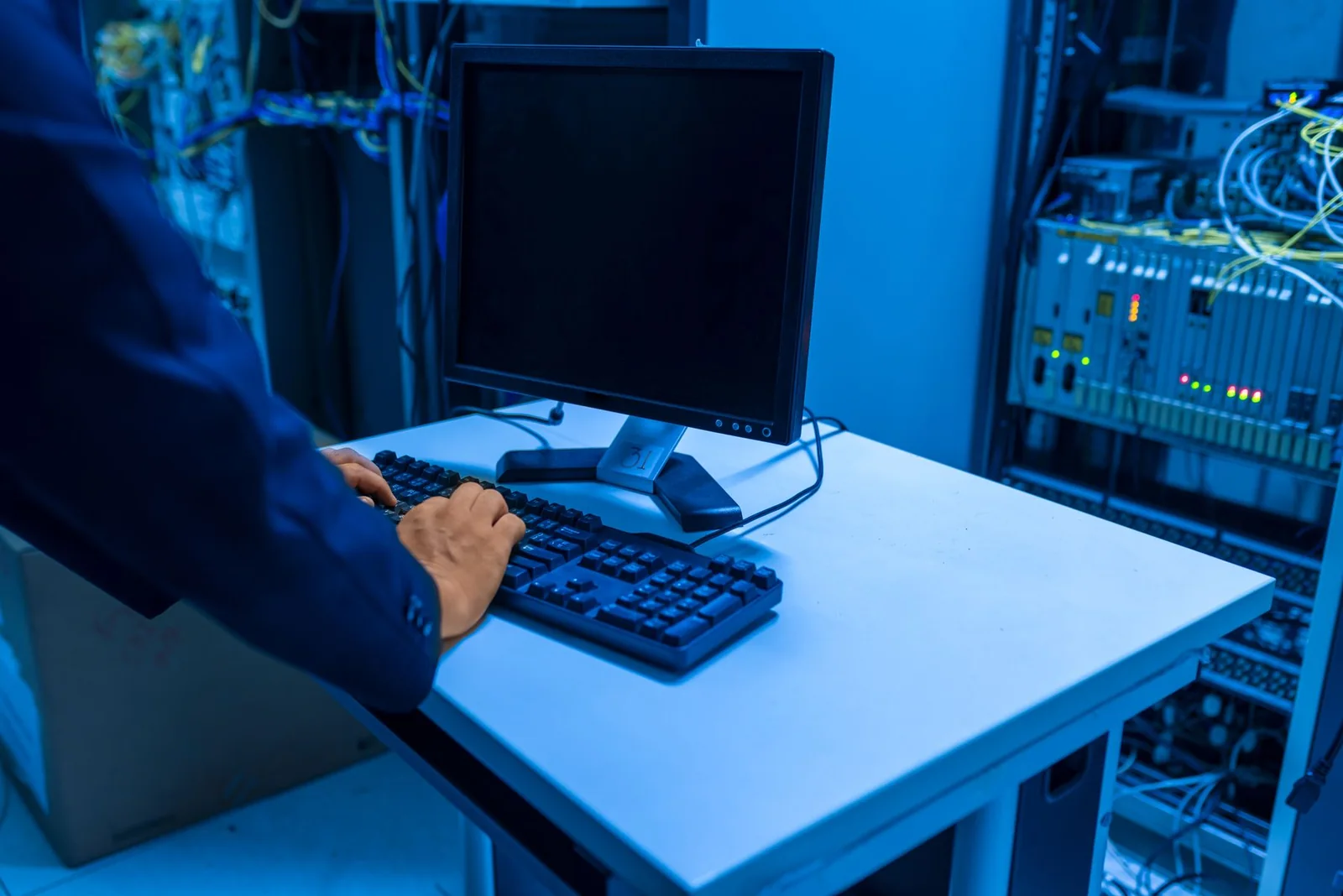 IT technician operating a workstation beside network equipment