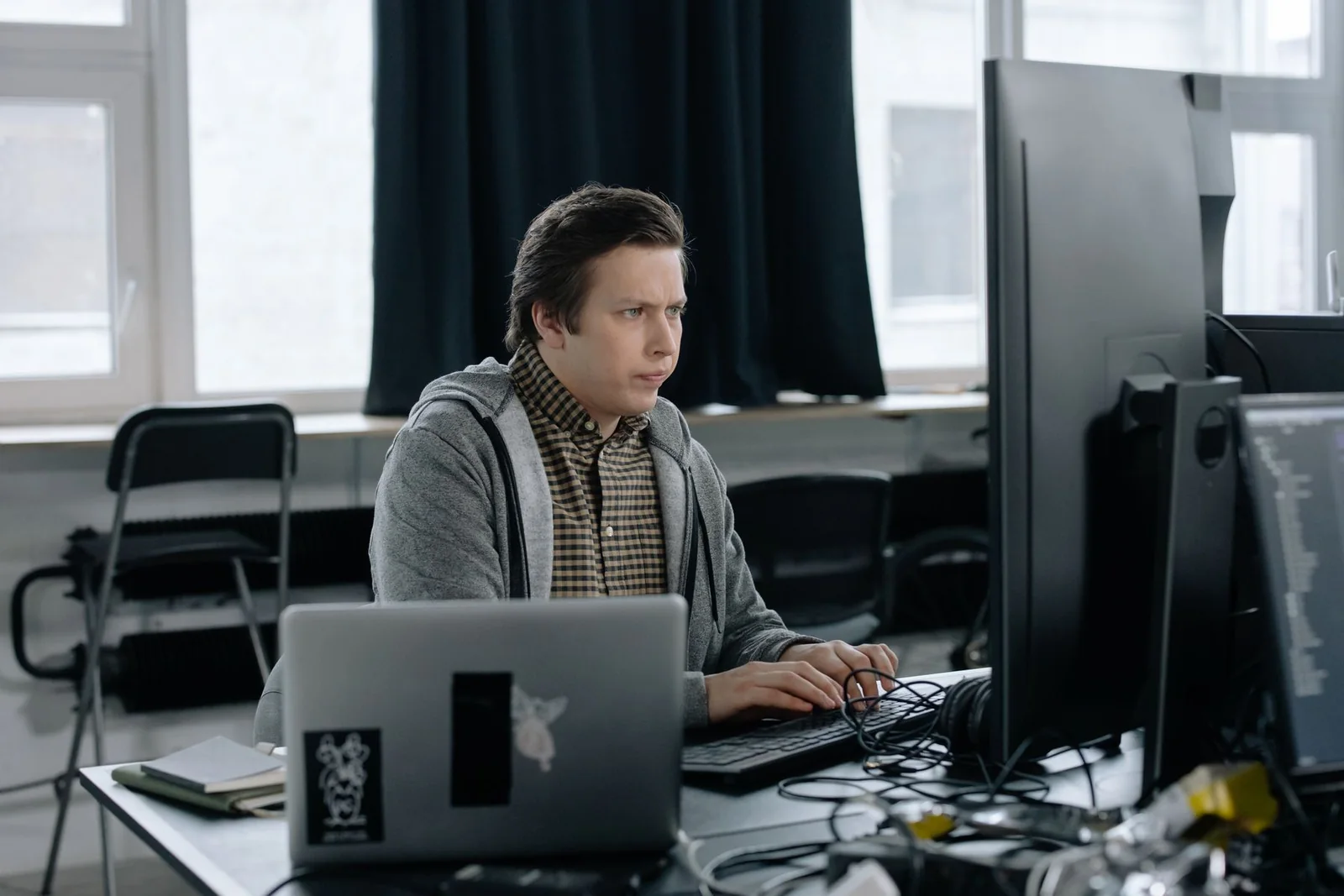 Programmer working between a laptop and desktop monitor